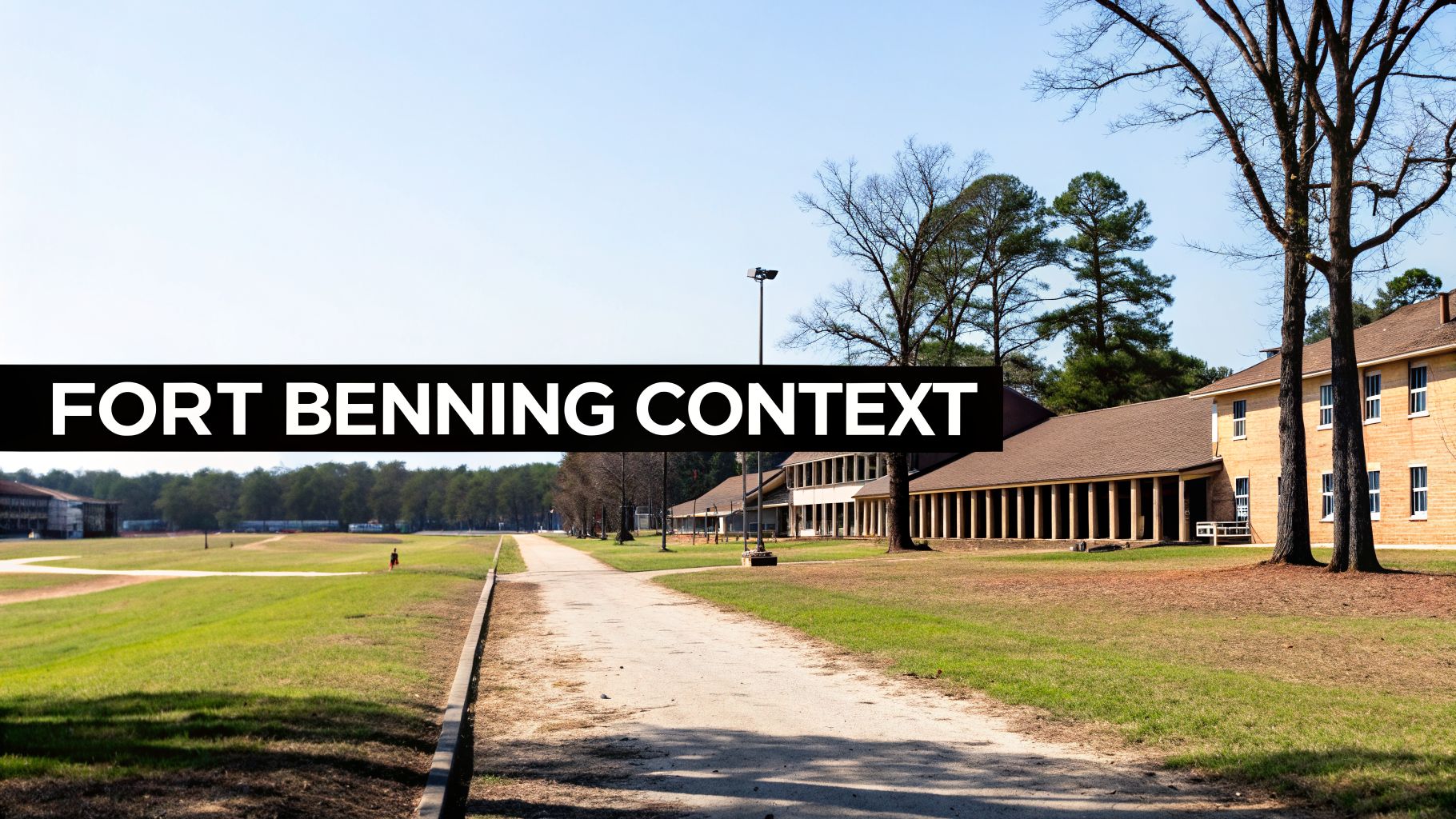 An outdoor view of Fort Benning with multiple military-style buildings, a dirt path, and green fields under a clear sky.